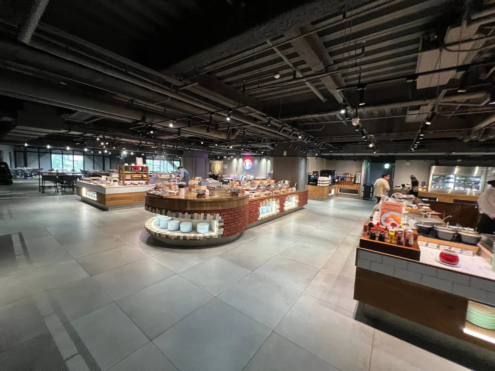 台中鳳凰酒店 B1 自助餐廳全景，工業風黑色天花板，中央是紅磚造型的圓弧取餐中島